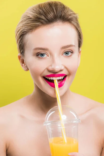 Happy pretty woman with orange juice in plastic cup isolated on yellow — Stock Photo