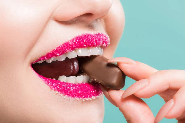 Vue recadrée de la femme avec du sucre sur les lèvres manger des bonbons au chocolat isolé sur bleu — Photo de stock