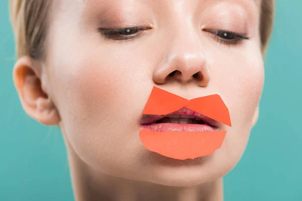 Schöne Frau mit orangefarbenem Papier auf den Lippen isoliert auf blau — Stockfoto