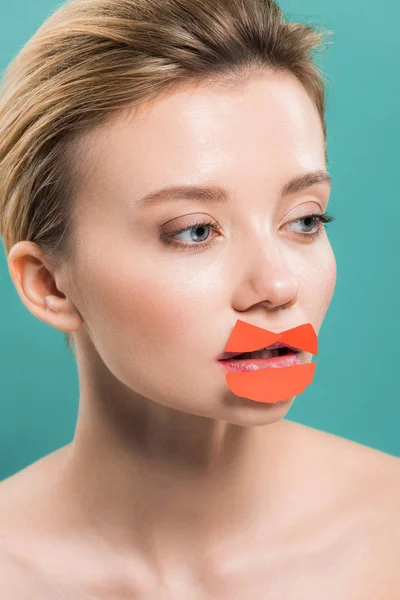 Schöne nackte junge Frau mit orangefarbenem Papier auf den Lippen isoliert auf blau — Stockfoto