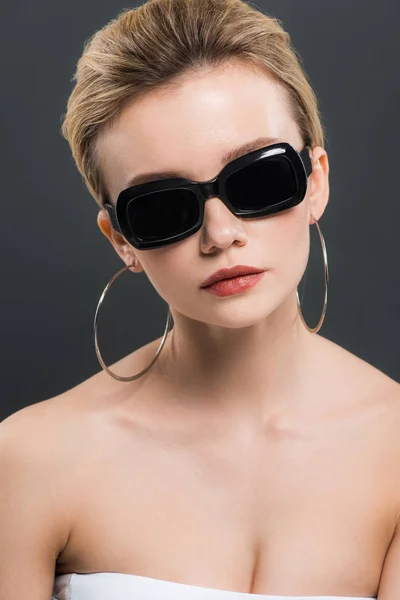 Стильная красивая молодая женщина в солнечных очках, изолированных на черном — стоковое фото