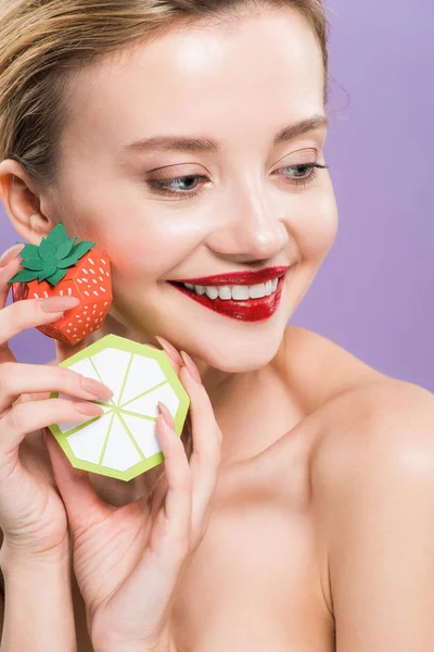 Feliz nu jovem segurando limão decorativo e morango isolado em roxo — Fotografia de Stock