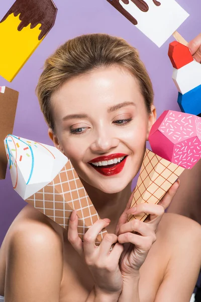 Cheerful naked woman holding decorative ice cream cones isolated on purple — Stock Photo