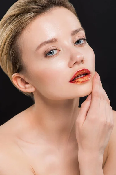 Nackte und attraktive Frau mit orangefarbenen Lippen, die Gesicht isoliert auf schwarz berühren — Stockfoto