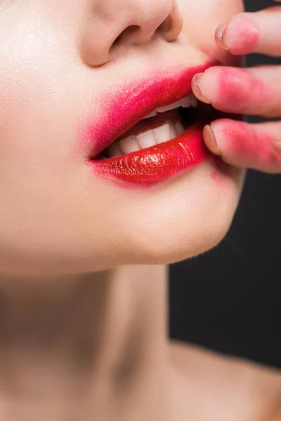Vista recortada de la mujer joven quitando lápiz labial rojo aislado en negro - foto de stock