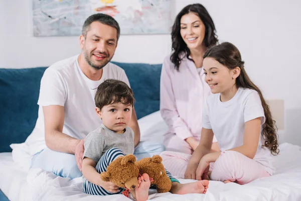 Selective focus of kids near happy parents in bedroom — Stock Photo