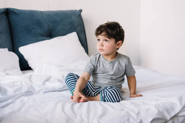 Cute kid with barefoot sitting on bed at home — Stock Photo