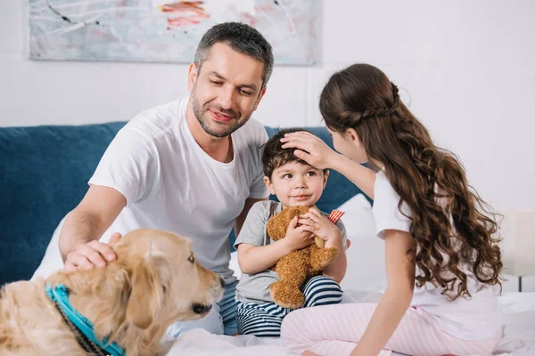 Messa a fuoco selettiva dell'uomo toccando golden retriever vicino ai bambini a casa — Foto stock