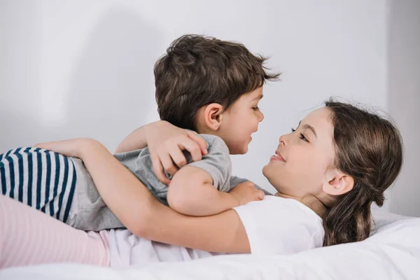 Fröhliches Kind umarmt fröhliches Kleinkind Bruder im Schlafzimmer — Stockfoto