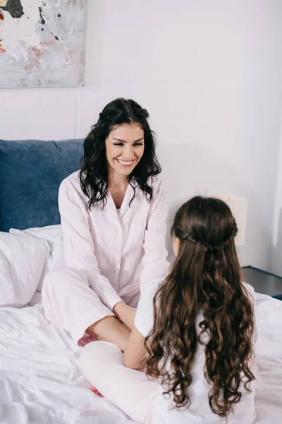 Селективное внимание счастливой матери, смотрящей на дочь в спальне — стоковое фото
