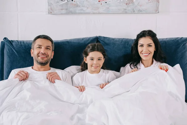 Parents heureux et fille mignonne regardant caméra dans la chambre — Photo de stock