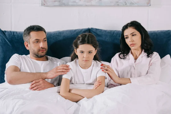 Genitori preoccupati toccando bambino sconvolto con le braccia incrociate in camera da letto — Foto stock