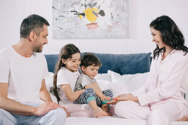 Glückliche Mutter lächelt neben niedlichen Kleinkind Sohn, Ehemann und Tochter — Stockfoto