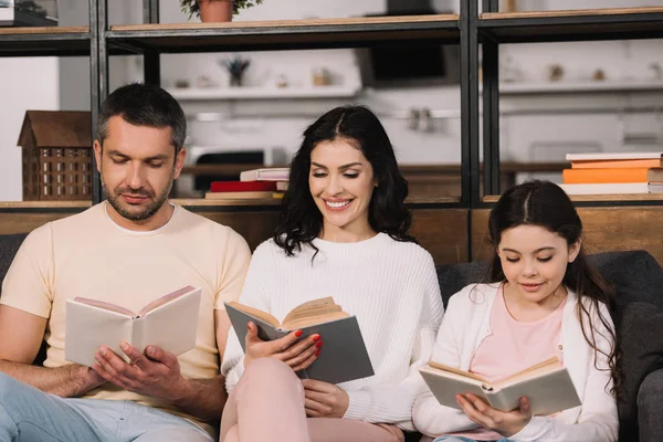 Щаслива сім'я сидить на дивані і читає книги у вітальні — стокове фото