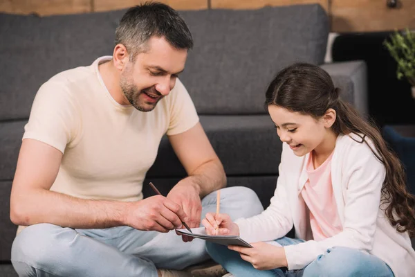 Happy father drawing with cheerful daughter in living room — Stock Photo