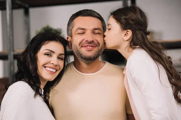 Bonito filha beijar bochecha de feliz pai perto atraente mãe — Fotografia de Stock