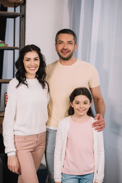 Счастливый мужчина, стоящий с милой дочерью и красивой женой дома — стоковое фото