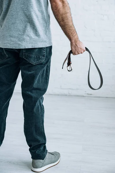 Cropped view of man holding leather belt at home — Stock Photo