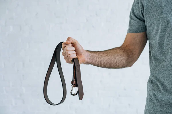 Cropped view of man holding leather belt at home — Stock Photo