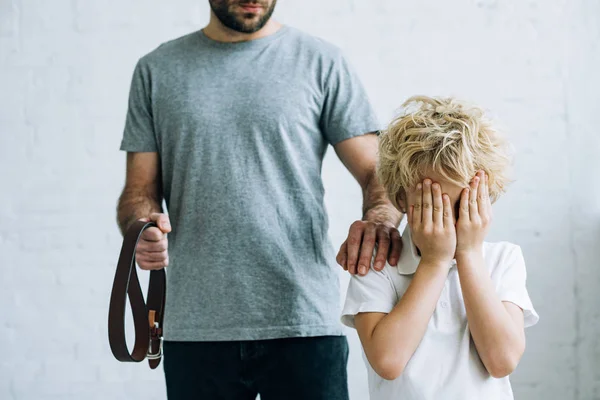Partial view of dad with belt and crying son at home — Stock Photo