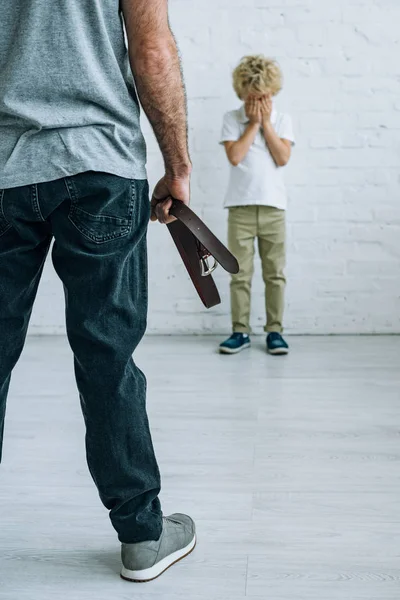 Vue partielle de papa avec ceinture et fils pleurant à la maison — Photo de stock