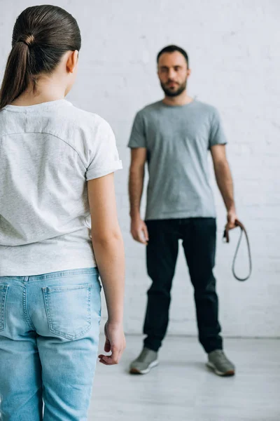 Back view of daughter looking at father with belt in hand — Stock Photo