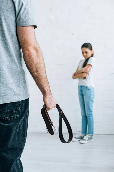 Vista ritagliata del padre che tiene la cintura e figlia sconvolta a casa — Foto stock
