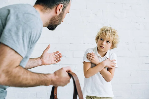 Vue recadrée du père tenant la ceinture et grondant fils à la maison — Photo de stock