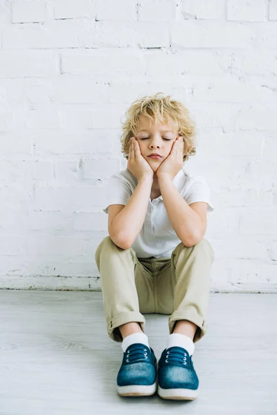 Niño preadolescente molesto sentado en el suelo en casa - foto de stock