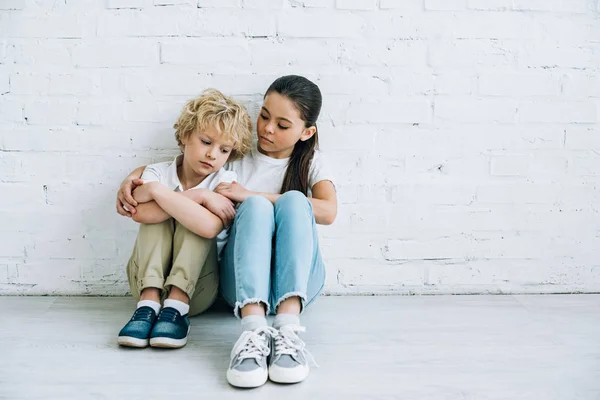 Sconvolto sorella e fratello seduto sul pavimento a casa — Foto stock