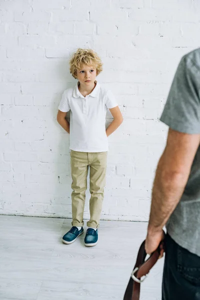 Cropped view of father holding belt and son having conflict — Stock Photo
