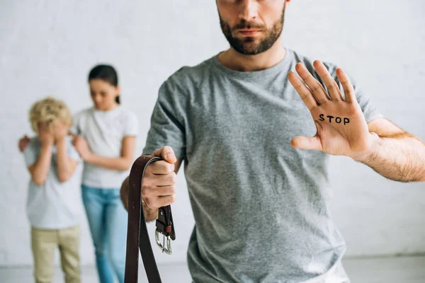 Partial view of abusive father with inscription on palm and sad kids — Stock Photo