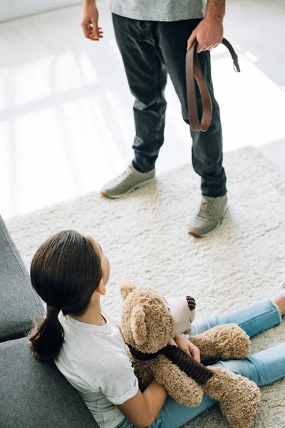 Overhead view of father with belt and daughter sitting on floor — Stock Photo