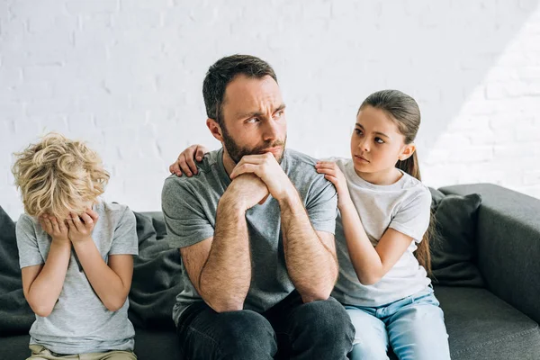 Dos tristes niños preadolescentes y padre teniendo conflicto - foto de stock