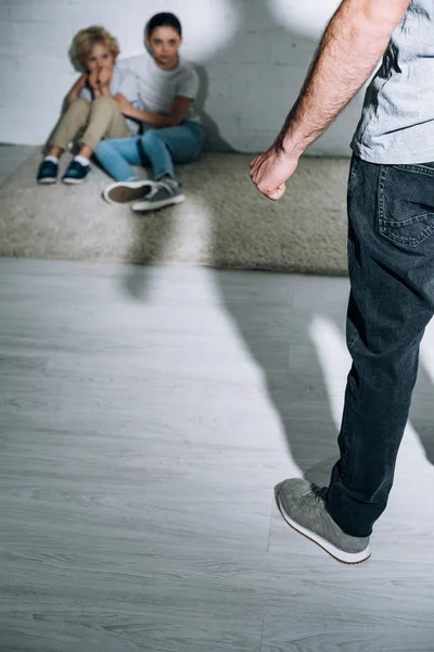 Cropped view of father and scared children sitting on carpet — Stock Photo