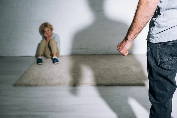 Частковий погляд на жорстокого батька і наляканого сина, що сидить на килимі — стокове фото