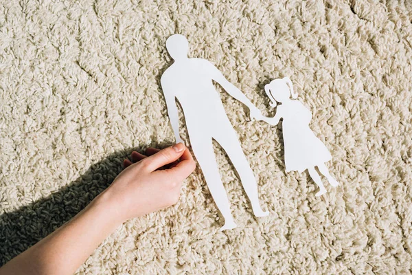 Partial view of woman with paper figures on carpet — Stock Photo