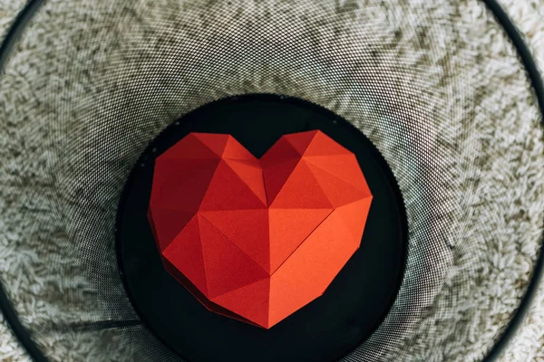 Red heart in black trash can on carpet — Stock Photo