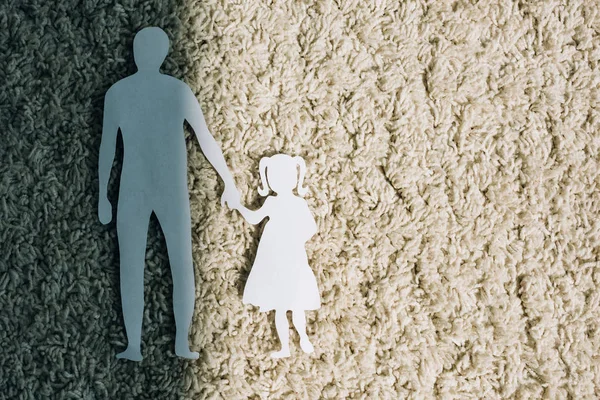 Top view of paper figures on carpet, domestic violence concept — Stock Photo