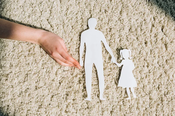 Partial view of woman with paper figures on carpet — Stock Photo