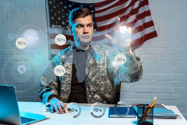 Guapo soldado en uniforme señalando con el dedo los diagramas porcentuales - foto de stock