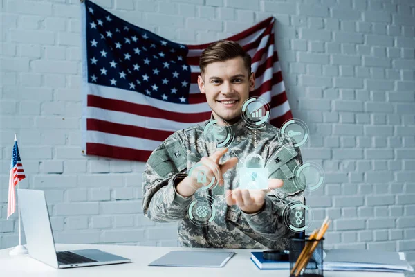 Cheerful man in military uniform pointing with finger at virtual padlock near laptop — Stock Photo