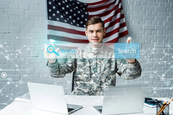 Hombre feliz en uniforme militar señalando con los dedos en la barra de dirección en la oficina - foto de stock