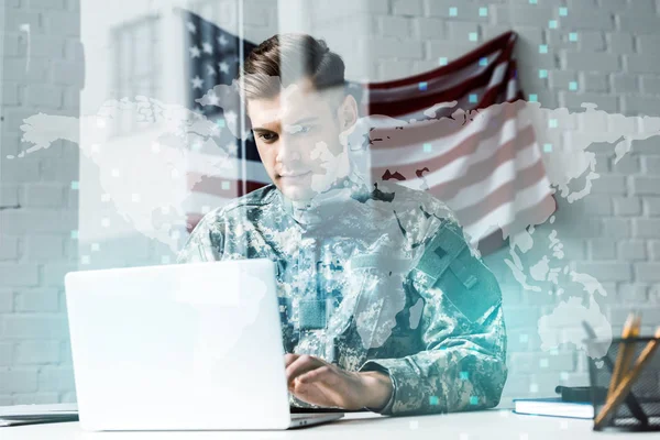 Soldat en uniforme de camouflage à l'aide d'un ordinateur portable au bureau près de la visualisation des données — Photo de stock