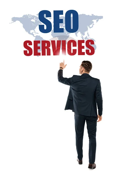 Vue arrière de l'homme pointant avec le doigt vers seo services lettrage tout en se tenant isolé sur blanc — Photo de stock