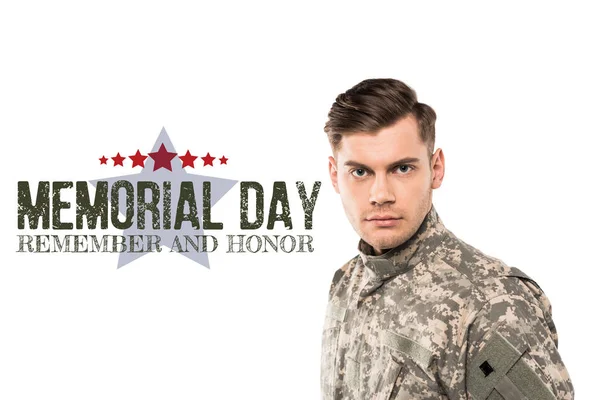 Serious and handsome soldier in uniform looking at camera near memorial day lettering on white — Stock Photo