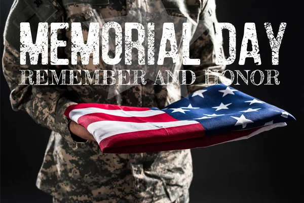 Cropped view of soldier in camouflage uniform holding flag of america near memorial day lettering on grey — Stock Photo