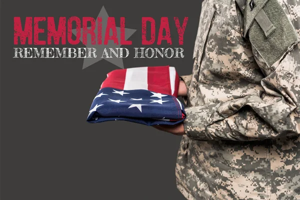 Abgeschnittene Ansicht eines Mannes in Militäruniform mit einer amerikanischen Flagge in der Nähe des Gedenktages Schriftzug auf grau — Stockfoto