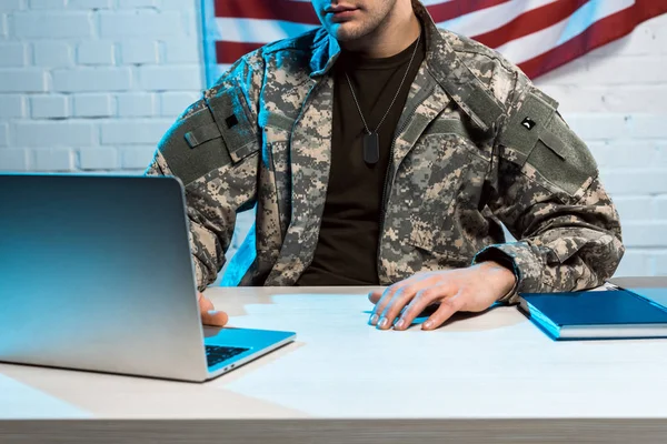 Vista ritagliata del soldato in uniforme utilizzando il computer portatile in ufficio — Foto stock