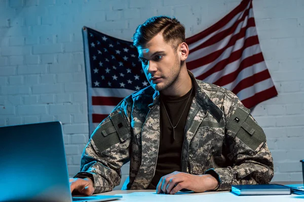 Guapo militar en uniforme sentado en la oficina y usando el ordenador portátil - foto de stock